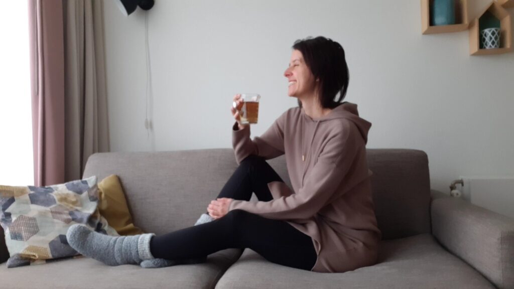 Marlies zit op de bank met een kop thee in haar hand