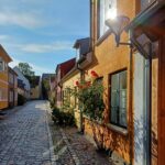 Straat in Odense met kleurrijke huisjes en de zon schijnt op één van de ramen.